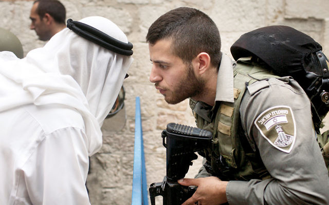 An Israeli border policeman talks to a Palestinian man near the scene of a stabbing attack in Jerusalem’s Old City last October. (Lior Mizrahi/Getty Images)