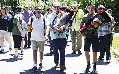 From left, Rabbi David Wizder; Leigh Nacht, carrying a Torah; past Beth El president Marty Kasdan, wearing a yellow vest; and Jarred Cohen, carrying another Torah. They’re all from Beth El, on their way to the future at Kol Dorot.