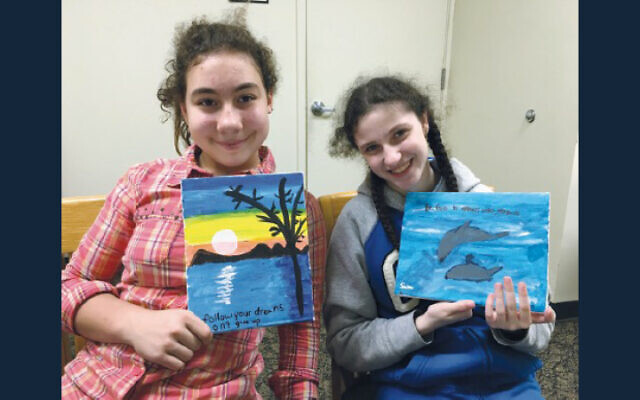 Two Sinai students hold up the art they’ve created. Two Sinai students hold up the art they’ve created.