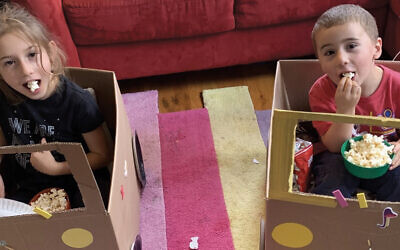 Temple Sharey Tefilo-Israel’s preschool sponsored a pandemic drive-in movie night; here, the synagogue’s Cantor Rebecca Moses’s children, Alexandra and Levi, munch popcorn in their “cars.” (TSTI)