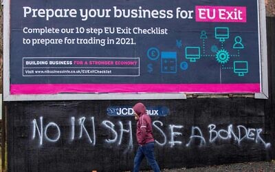 A man walks past a sign promoting Brexit and graffiti against an Irish sea border, in Belfast, Feb. 2, 2021. (Paul Faith/AFP via Getty Images)