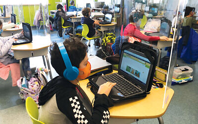 Masked, separated students study in a classroom at Gottesman RTW.