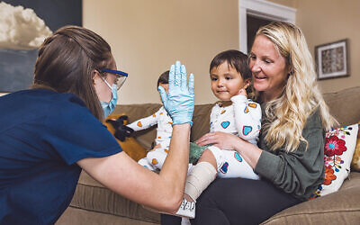 A young patient being by a DispatchHealth medical professional at home.
