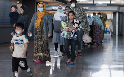A family evacuated from Afghanistan is led through the arrival terminal at Dulles International Airport in the Washington area in August to board a bus that will take them to a refugee processing center. (Anna Moneymaker/Getty Images)