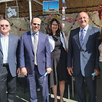 From left, Sinai’s associate managing director Arielle Greenbaum Saposh, managing director Sam Fishman, dean Rabbi Dr. Yisrael Rothwachs, development director Pam Ennis, and communications director Abigail Hepner Gross stand with Holy Name’s CEO Michael Maron, who is second from right. They’re all at the hospital’s annual Sukkot Lunch and Learn, in its sukkah, which flooding from Ida moved to the employee cafeteria patio. Mr. Maron drew on writing by Rabbi Jonathan Sacks to talk about coming together in crisis. Many members of Holy Name’s staff — not all of them Jewish — come to the lunch, and they invite members of partner agencies to join them. (Jeff Rhode)