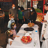 Teaneck’s Temple Emeth congregants and their children learned about Sukkot and enjoyed pizza in and goodies in the shul’s sukkah with Rabbi Steven Sirbu and Cantor Ellen Tilem, standing at the right. (Barbara Balkin)