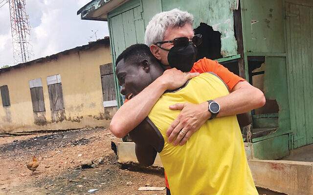 In Ghana in July 2021, Evan Robbins and Cephas, who is training to become a mason, hug.