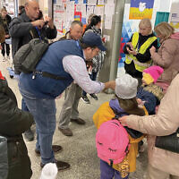 Krakow’s central train station has become a processing center for refugees. Here, Rabbi David-Seth Kirshner of Temple Emanu-El 
of Closter and volunteers give candy 
to refugee children. (Courtesy Jodi Scherl)