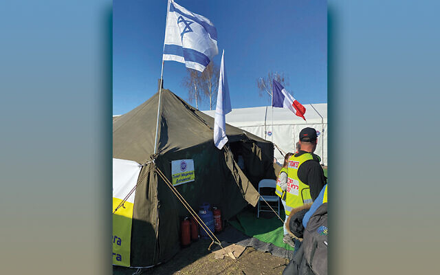 An Israeli flag flies over the first humanitarian booth refugees see as they cross the border at Medyka.
