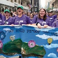 Students from Ma’ayanot Yeshiva High School for Girls in Teaneck stand behind their banner, and beside each other.