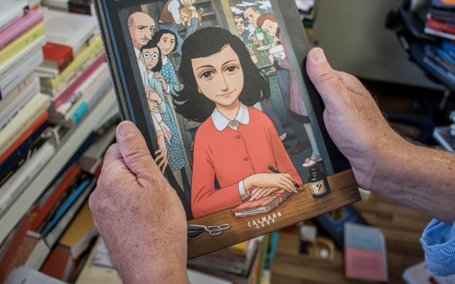 A man holds a copy of the graphic novel version of "The Diary of Anne Frank", by Israeli writer-director Ari Folman and illustrator David Polonsky. (Stringer/AFP via Getty Images)