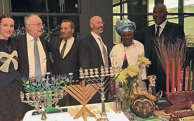 Lady Anya and Clive Gillinson, Rabbi Shmuley Boteach, Elisha Wiesel, DeBra Oguamah, and Robert Smith stand by chanukiot and kinaras, ready to celebrate the two holidays