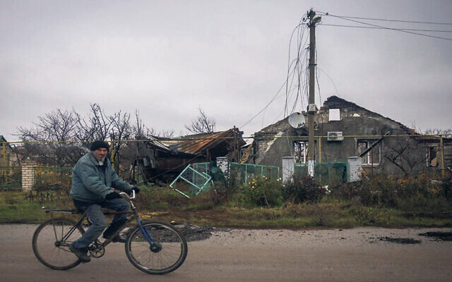 A man rides a bike past a destroyed house in the village of Posad Pokrovske, on the outskirts of Kherson, Ukraine, on Nov. 30. (Chris McGrath/Getty Images)