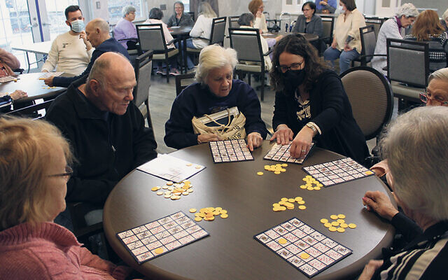 Federation staffer Naomi Knopf helps a group of seniors play Pokeno.