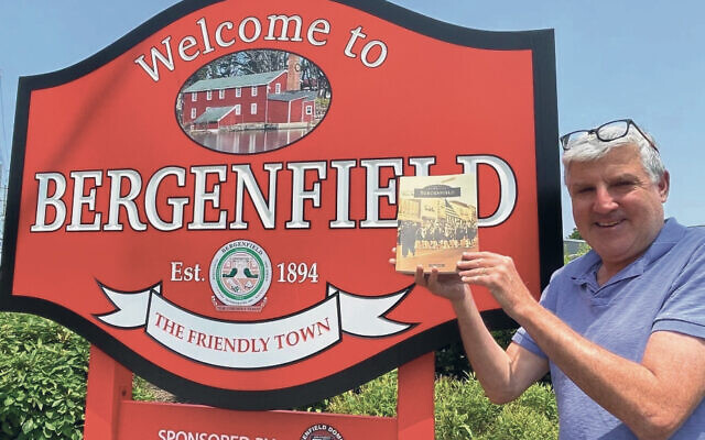 Jay Levin holds up his new book as he welcomes people to Bergenfield.