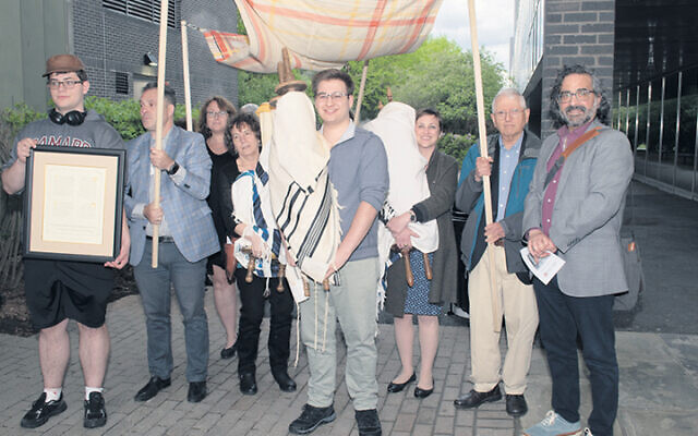 Community members walk the rescued Torah, under a chuppah, to its home at Ramapo College.