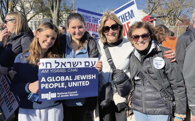 From left, Joan Ornstein’s granddaughters, Gallie Nathanson and Maya Ornstein, holding the sign, stand next to Ms. Ornstein and Paula Star. (Courtesy NCJW BCS)