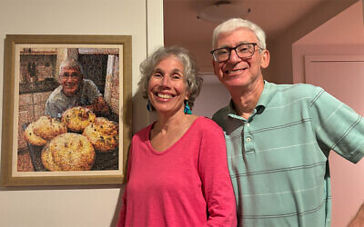 Merrill and Andy Silver stand in front of a photo of Andy; it’s made of images of him with challot he’s baked over the years.