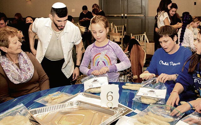 Idan Chabasov helping participants get started with their braiding at his workshop in Mahwah.