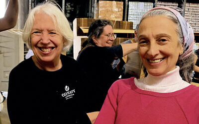 Former Teaneckers Leah Moskovits, left, and Abigail Klein Leichman assemble boxes for field rations on an IDF base in central Israel. (Malka Shrybman)