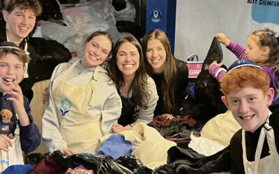 Lauren Turk of the Hangout, center, celebrates her store’s 5th anniversary by packing boxes of clothing for Israel with friends and family at Yad Leah.