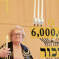 Honoree Miriam Rak lights a candle, assisted by Allen Zaks.