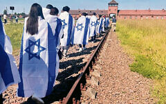 Kushner students, wrapped in Israeli flags, walk on the train tracks to Auschwitz. (All photos courtesy Ariel Horn Levenson)