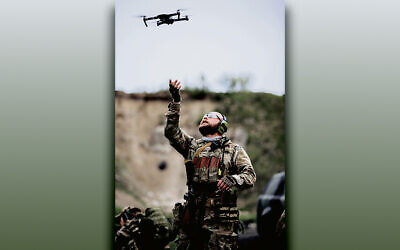 A Ukrainian soldier gestures up toward a drone.