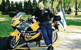 Lenny Mandel stands in front of the motorcycle, complete with Iraeli flag, that his friend Bobby rode up to West Point.