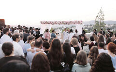 Miriam and Chaim stand under a chuppah decorated by Michlelet campers.