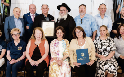 Seated, from left: Assemblywoman Lisa Swain (D-38), Commissioners Dr. Joan Voss and Mary Amororo, Bris Avrohom associate director Rebbetzin Shterney Kanelsky, Commissioner Tracy Silna Zur, sponsor Tanya German, and Commissioner Germaine Ortiz. Standing, from left: Bris Avrohom board member Mark Rekhtmen, Bergen County Clerk John Hogan, County Executive James Tedesco III, Bris Avrohom executive director Rabbi Mordechai Kanelsky, Commissioner Thomas Sullivan, sponsor Vlad German, and a representative from the sheriff’s office. (Courtesy Bris Avrohom)