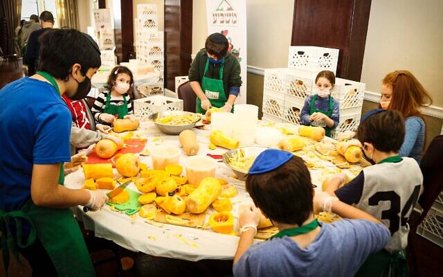 Children and adults prepare food at West Side Institutional Synagogue to feed the needy as part of Family Chesed Day, Dec. 12, 2021. More than 100 volunteers led by Rabbi Daniel Sherman prepared meals to be delivered to the Masbia Soup Kitchen Network. (Courtesy Masbia)