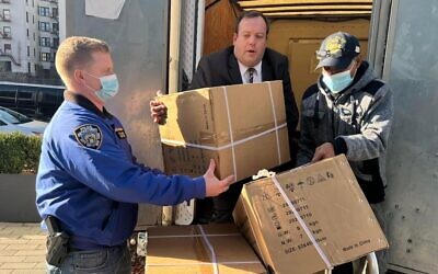 NYPD Community Affairs Officer Robert Adams; Mendy Mirocznik, president of the Council of Jewish Organizations of Staten Island, and Joida Quinones of the NYC Test & Trace Corps unload supplies, personal protective equipment, food and masks to fight Omicron at a recent food distribution and resources giveaway on Staten Island. (Courtesy COJO)