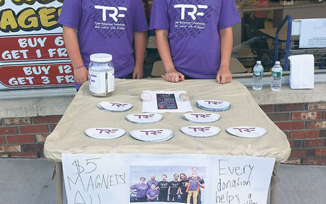 Geoffrey and his friend Hannah Zwim sell TRF logo car magnets outside a local business.