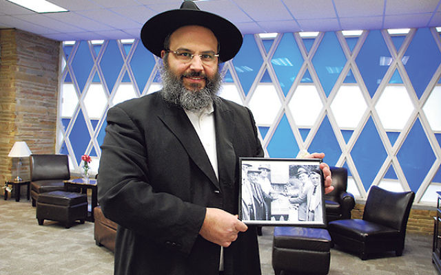 Rabbi Moshe Hezrony holds up a photo of synagogue leaders taken in the mid-1950s, around the time ground was broken for the Congregation Anshei Roosevelt building.