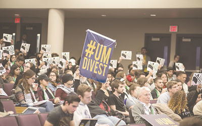 Audience members hold signs that read "Stop Silencing Us!"prior to the University of Michigan student government vote on BDS.