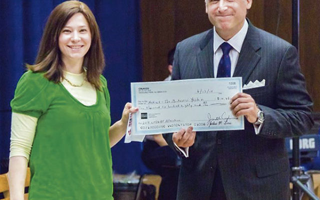 Michelle Klein Pincus, a cnjKids board member, presents a check to Netivot board president Jeffrey Schreiber to be used to give parents a credit on their tuition.
