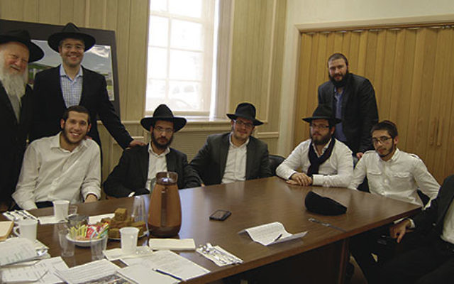 Rabbi Moshe Herson and Rabbi Mendel Solomon, left, standing, gather at the Rabbinical College of America with students who helped organize Passover seders around the world, from left, Zev Rosenblum, Mendy Wilschanski, Mendel Wuensch, Levy Dray, Yehuda Iva