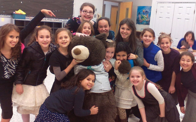 Head girls’ “chiller” Sarah Mintz, fourth from right, with East Windsor Chillers and the nearly life-sized stuffed bear won by one of the girls. 