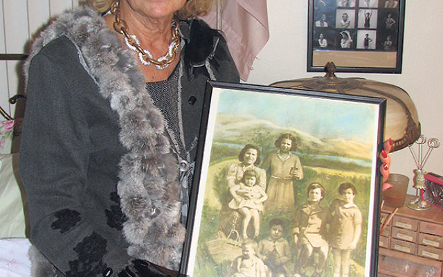 Paulette Dorflaufer in her Livingston home, holding a photo of herself as an infant, her mother, and four siblings. The siblings and her mother were murdered in Auschwitz. 