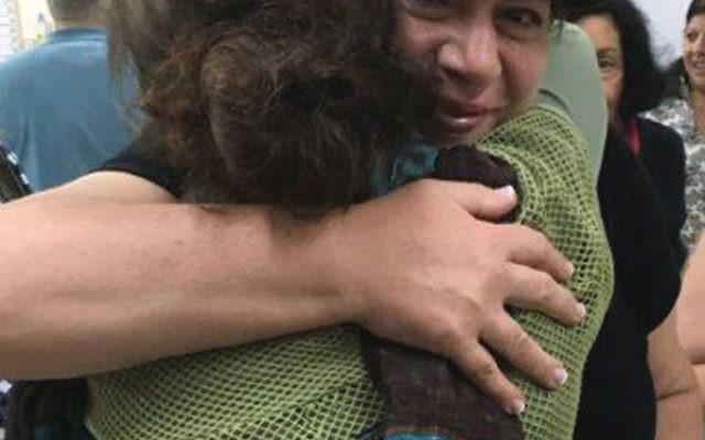 Cheryl Minkoff of Highland Park, facing the camera, hugs a client of Amit Shikum, who talked about recovering from mental illness to members of a federation mission.
