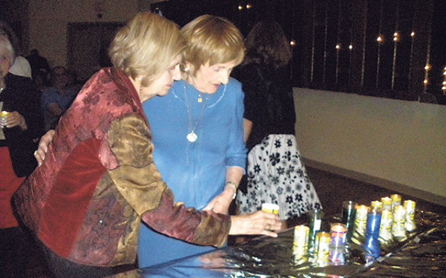 Holocaust survivors Tova Friedman, left, and Devorah Hilsenrath, both of Highland Park, light candles in memory of those lost in the Shoa.