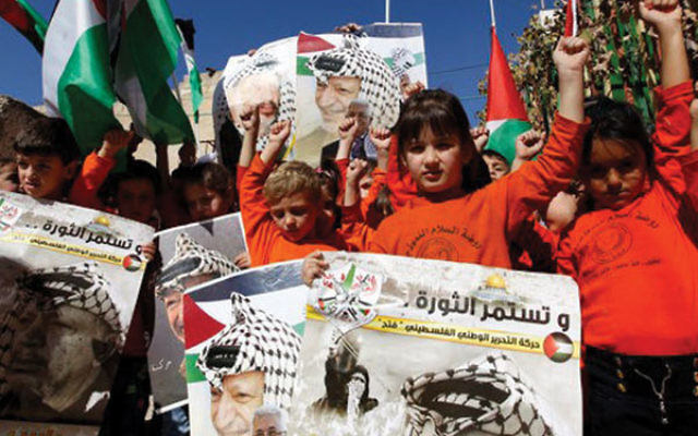 Palestinian children hold posters with the picture of former Palestinian leader Yasser Arafat and current Palesttinian Authority President Mahmoud Abbas during a rally in Hebron on Nov. 10, 2016, marking the 12th anniversary of Arafat’s death.