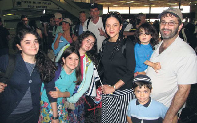Kim and Mitchell German — with their children, from left, Sarah, Arielle, Yael, Yosef (being held by Mitchell), and Yehuda — at JFK International Airport as they make aliya to Israel. Despite the war with Hamas, Kim German said, she had &ldquo