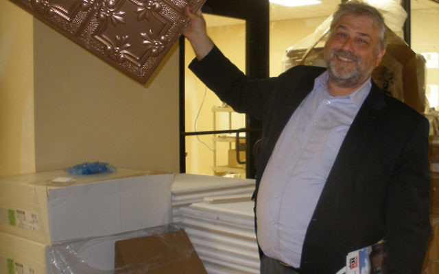 Rutgers Hillel executive director Andrew Getraer holds up a ceiling tile to be used in the new dining hall.