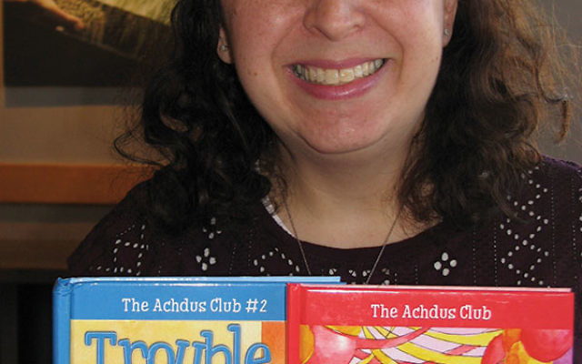 Author Faygie Holt with The New Girl and Trouble Ahead, the first two books in her children’s series “The Achdus Club.” 