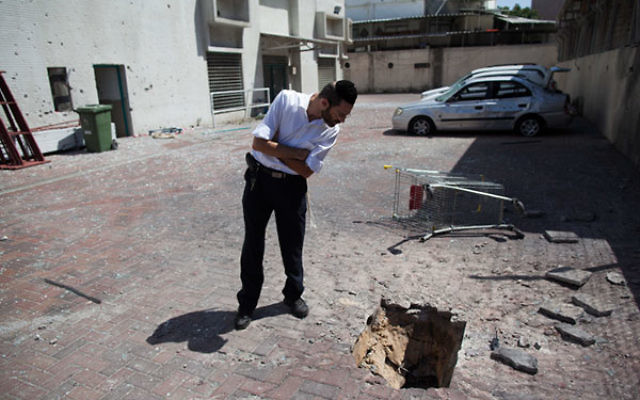 An Israeli inspects the damage from a Palestinian rocket strike outside a store in the southern Israeli city of Ashdod, July 9, 2014.