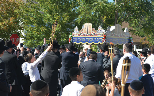 Hundreds accompanying the new Torah scroll danced and sang through Highland Park.