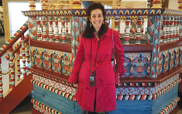 During a visit to trace her family roots in Poland, Lynne Azarchi stands in front of a reconstructed wooden synagogue in Warsaw’s POLIN Museum of the History of Polish Jews.