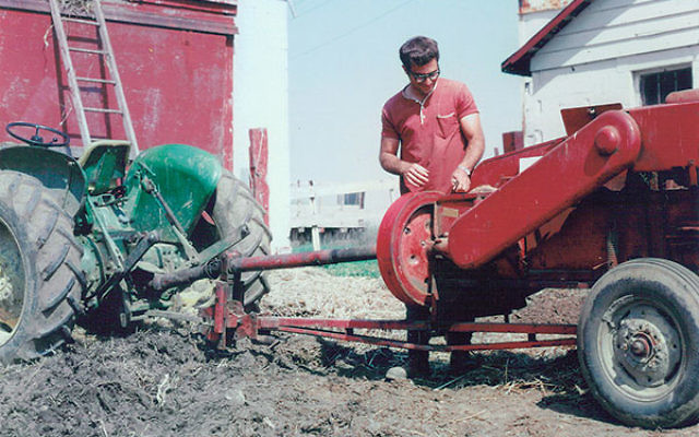 Micha Livne repairs a hay baler while serving as a shaliah on the Hechalutz Farm in the late ’60s.